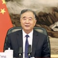 Wang seated with Chinese flag and landscape painting in background