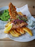 Tofish on chips, garnished with salad and a lemon slice, mushy peas and tartare sauce on the side
