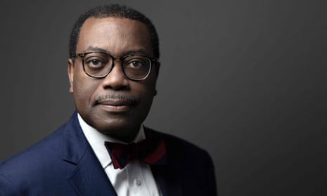 An African man in glasses, a suit and bow tie, poses for a photograph