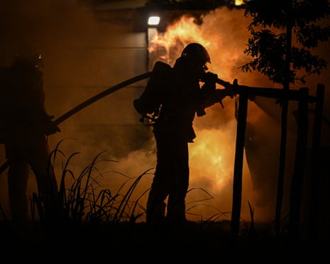 A firefighter sprays water on burning cars during a fire in front of a camping site in Villeneuve-les-Beziers, southern France.