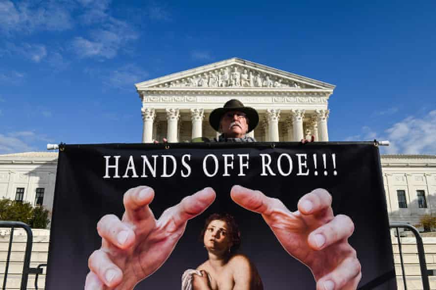 A man holds a sign supporting Roe v Wade in front of the supreme court building in Washington DC on 30 November.
