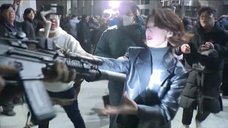 Ahn Gwi-ryeong, spokesperson for the opposition Democratic party, grabs the gun of a South Korean solider outside the national assembly