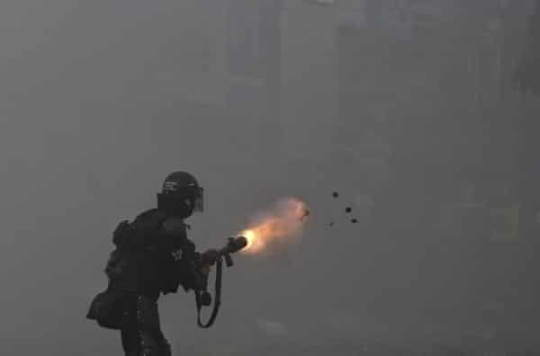 A police officer fires tear gas