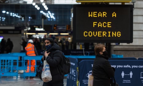Pedestrians walk past a ‘Wear a face covering’ message displayed outside Victoria Station