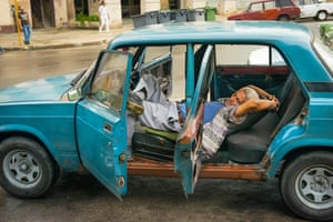 A man lies down for a siesta in blue Lada in Havana.