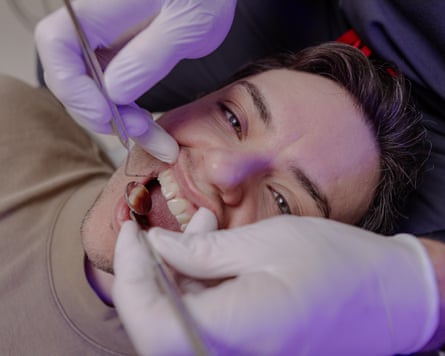 Closeup of a dentist’s gloved hands holding open a man’s mouth with dental instruments