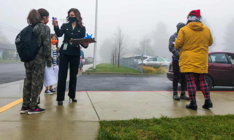 lady wearing black checks temperature of a kid with a digital thermometer