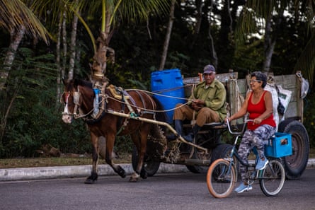 A horse-drawn cart and woman on a bicycle on the road in Playa Larga.