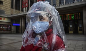 A Chinese boy is covered in a plastic bag for protection as he arrives from a train at Beijing Station