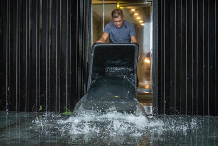 A worker uses a large basin to remove flood water from a hotel