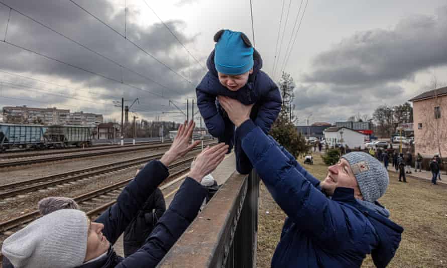 Oleg (R), who decided to remain in Irpin, passes his son Maksim over a fence to his wife Yana, before the arrival of an evacuation train to the city of Kiev (Kyiv), at the train station in Irpin, Ukraine, 04 March 2022.