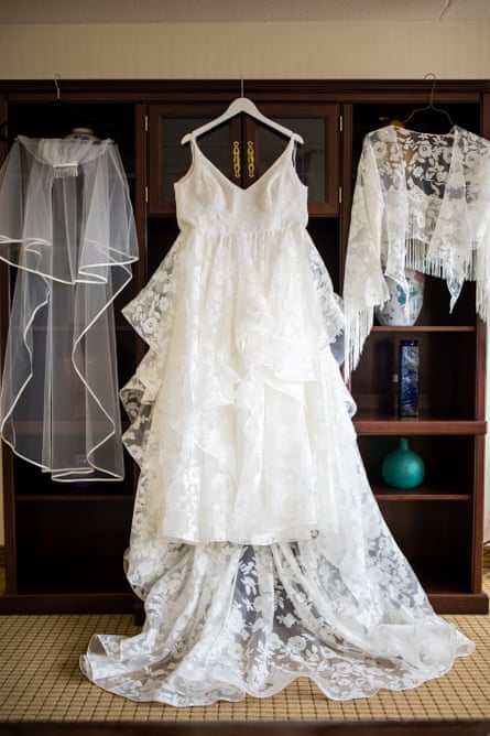 A wedding dress and veil hanging from some shelves.