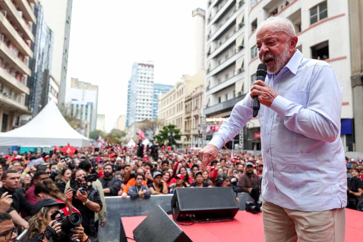 A middle-aged man with a microphone addresses a large crowd.