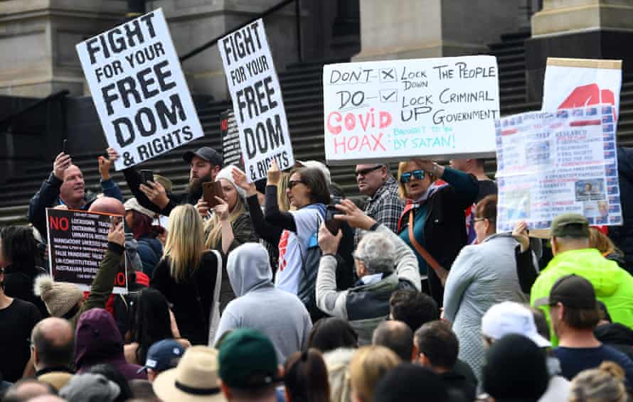 Anti-lockdown protesters hold placards on the steps of Victoria’s state parliament in Melbourne on May 10, 2020.