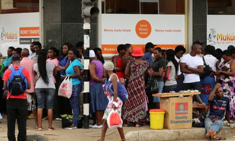 People queue to withdraw money from a bank in Harare