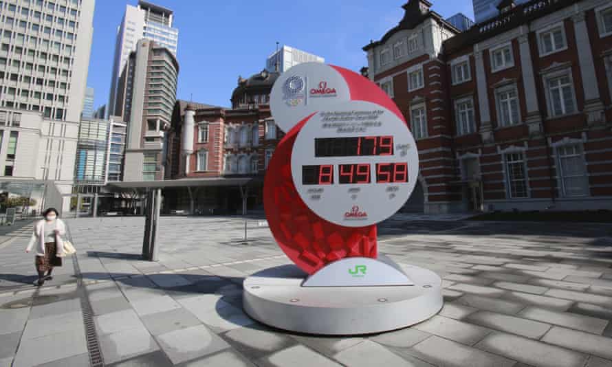 A woman walks past a Tokyo Olympic and Paralympic Games countdown clock at Tokyo station
