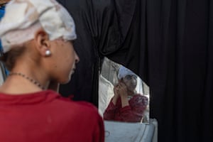 Hala adjusts her earring while looking into a broken mirror