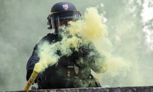 An anti riot police officer throws back a flare during a demonstration against the mandatory Covid-19 health pass to access most of the public space, in Nantes, western France.