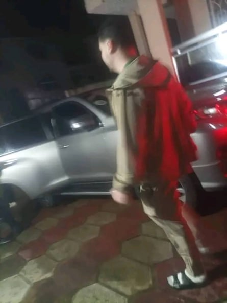 Blurred image from behind of a man standing next to some cars.