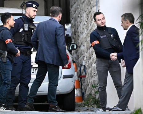 France's former president Nicolas Sarkozy (R) shakes hands with a police officer as he leaves his residence to present himself to La Santé prison for incarceration in Paris, on 21 October 2025.