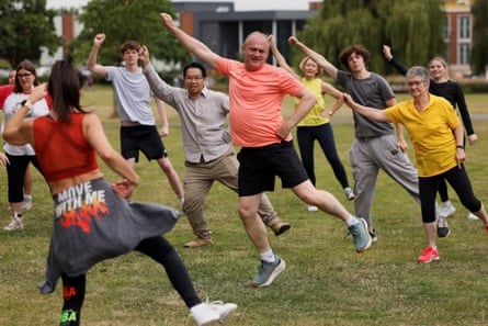 Ed Davey in an orange T-shirt and black shorts joins Zumba dancers in a park