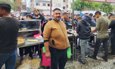 Fahd al-Af smiles as he stands in front of people serving food to customers