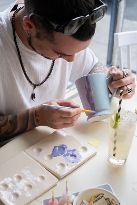 A young man paints a mug