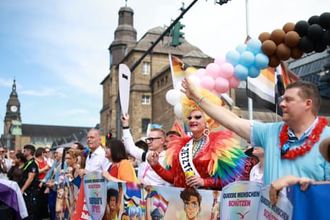 People watch the Hamburg Pride march with balloons and flags.