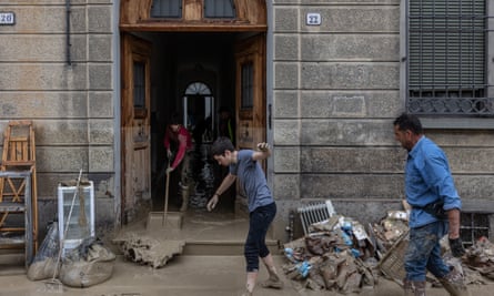 People sweeping mud from a house after torrential rain caused severe flooding and landslides, Faenza, Italy, 18 May 2023.