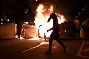 A protester walks past burning rubbish containers during clashes with the Catalan police force after a demonstration last week in Barcelona