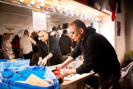 Heklina in a dressing room, wearing black, in the process of doing her makeup