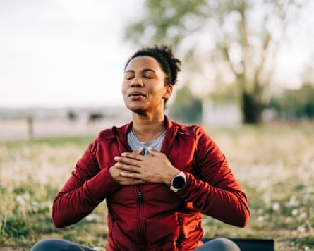 woman sat cross-legged, breathing with her eyes closed