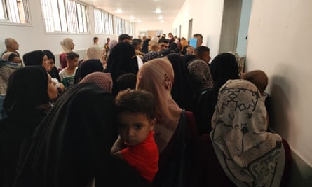 Families cram into a narrow hallway in a medical centre.