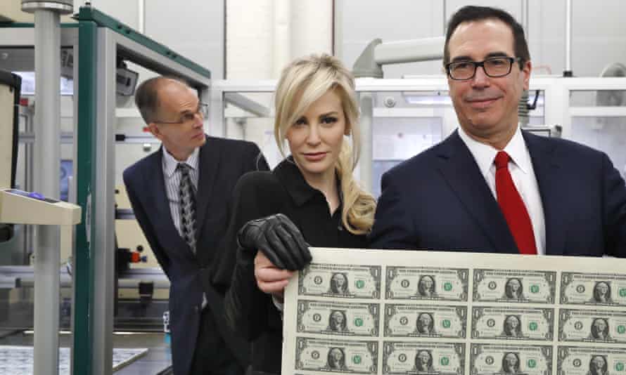 Treasury Secretary Steven Mnuchin, right, and his wife Louise Linton, hold up a sheet of new $1 bills, the first currency notes bearing his and U.S. Treasurer Jovita Carranza’s signatures.