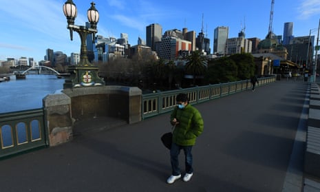 A person wearing a face mask walks across Princes Bridge in Melbourne