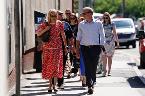 A couple walking in front of several others.