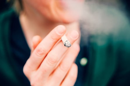 a hand holds a lit cigarette