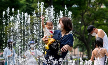 A woman with a child in a  fountain at a park in Nakano, Tokyo,  in June