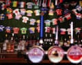 A bar with beer taps up front and bottles of spirits lined up under strings of bunting depicting football tops in the national colours of the teams competing in the World Cup.