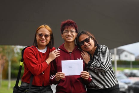 Ethan Rillon holding up his results paper with his sister and mother standing by his side.