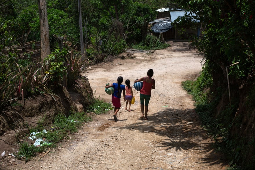 Girls carry water jugs after filling them in a nearby stream in Tizamarte, Camotán, Chiquimula, Guatemala.