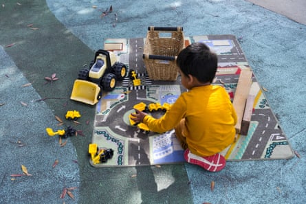 A child playing with building and transport toys on a road map.