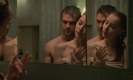 man and woman in a bathroom looking in a mirror in a film still
