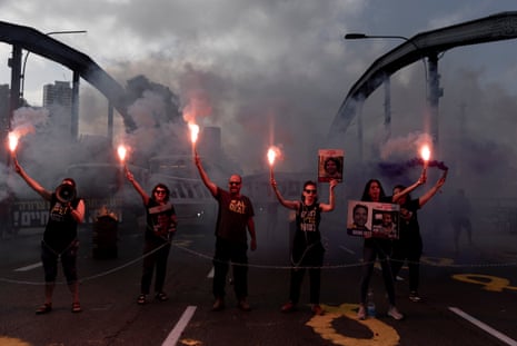 One man and five women stand on a smoke filled bridge holding red flares and conducting a protest