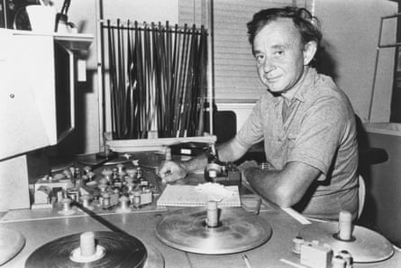 Black and white photo showing a man sitting at an editing desk, with spools and film in front of him.