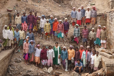 About 50 Indian men and women posing for a group portrait while standing in a large pit with walls on either side