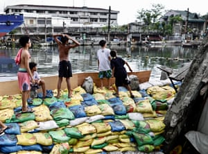 Children play on top of sandbags piled high to reinforce a damaged dike