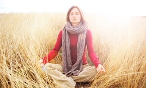 Young woman meditating in peace radiating light in a long grass field