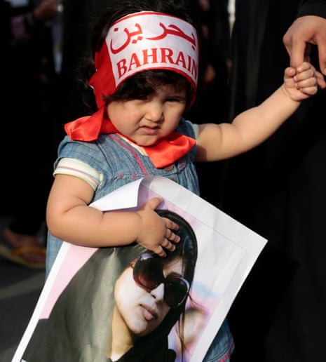 A girl wearing a headband that reads “Bahrain” in English and Arabic holds a poster of jailed opposition human rights activist Zainab al-Khawaja