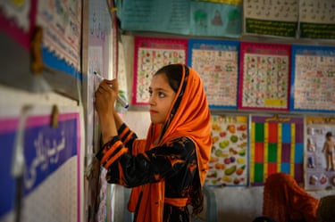 A girl writes on a whiteboard in a brightly decorated classroom